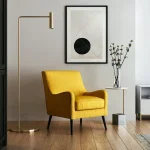 A modern living space with a mustard-yellow armchair, a gold floor lamp, a small side table with a vase of flowers, and abstract wall art.